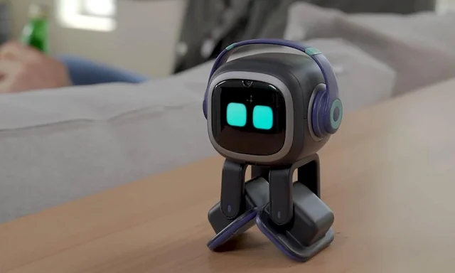 EMO robot standing on a tabletop beside a sofa